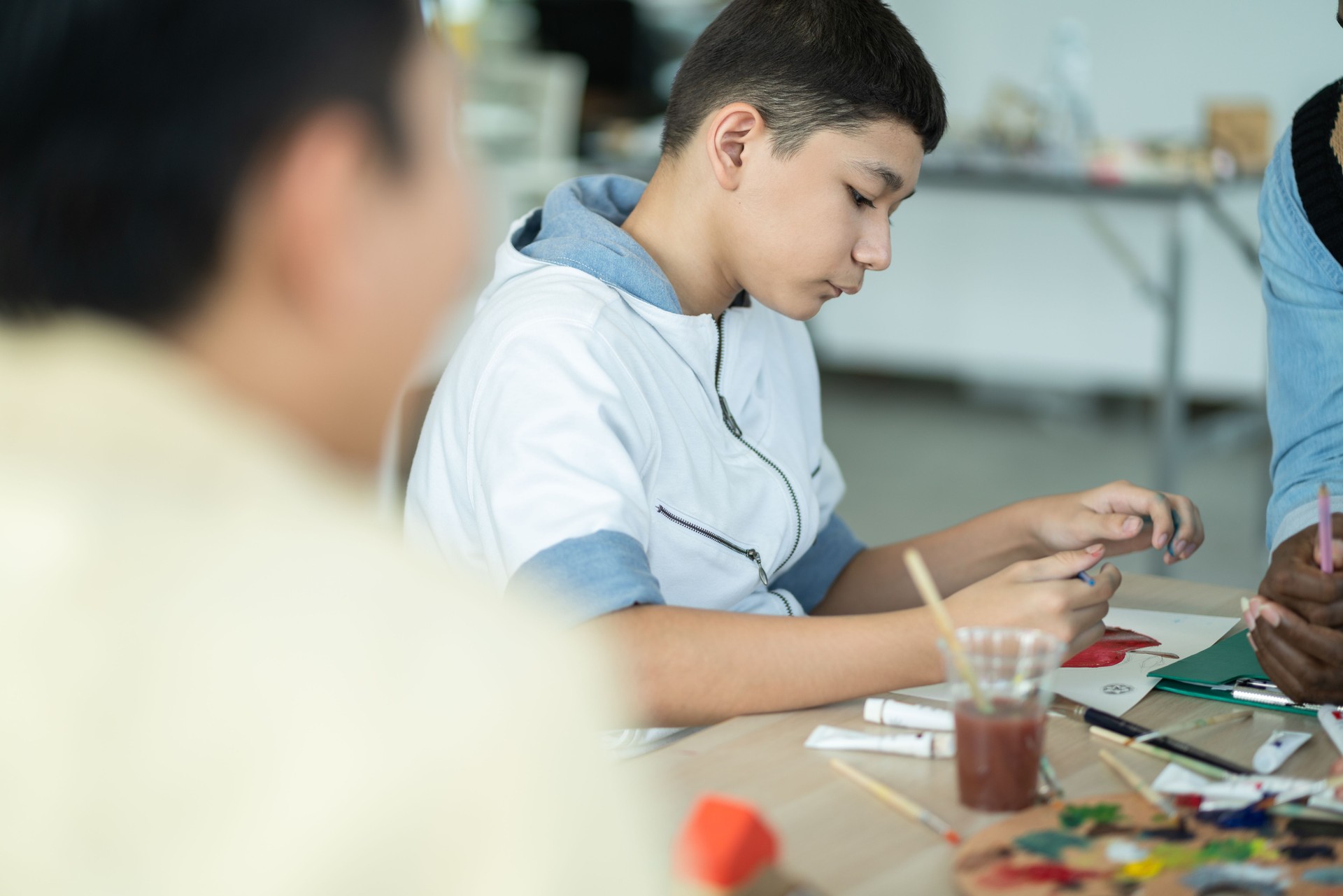 Boy enjoy drawing and painting in arts class. kid using paintbrush sketch on paper. practicing art skill, teacher support creative thinking idea. school activity, learning and education concept