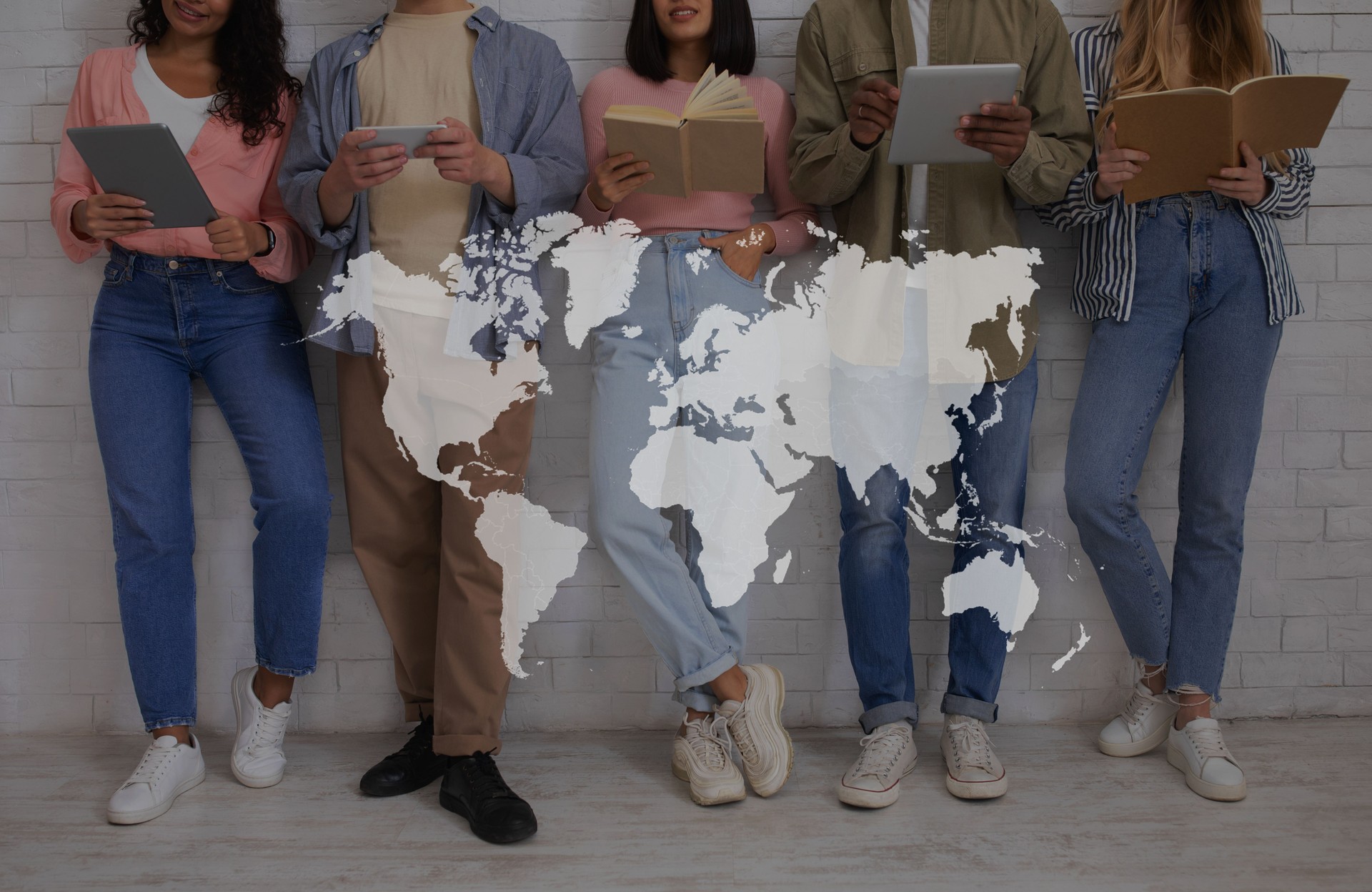 Education, international relations and student exchange. Young multiracial people with books and gadgets read